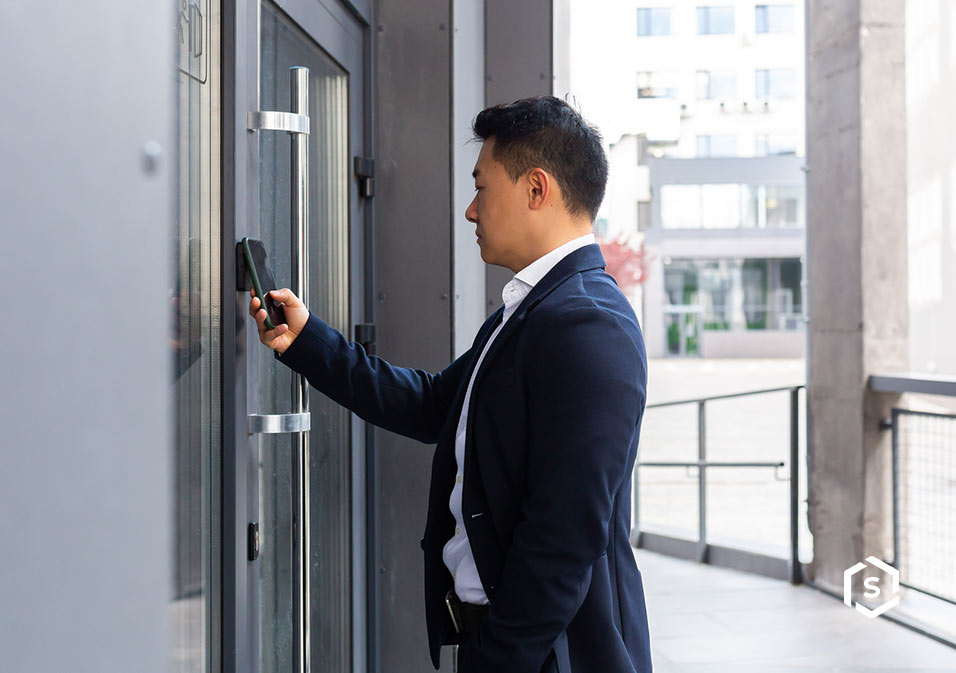Homem em um prédio moderno usando smartphone para abrir porta ou verificar uma correspondência na caixa de correio inteligente
