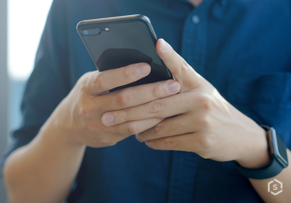 Síndico respondendo grupo de whatsapp do prédio no smartphone, vestindo camisa azul, em ambiente moderno, com foco no celular e na mão. Síndico respondendo grupo de whatsapp do prédio no smartphone, vestindo camisa azul, em ambiente moderno, com foco no celular e na mão.