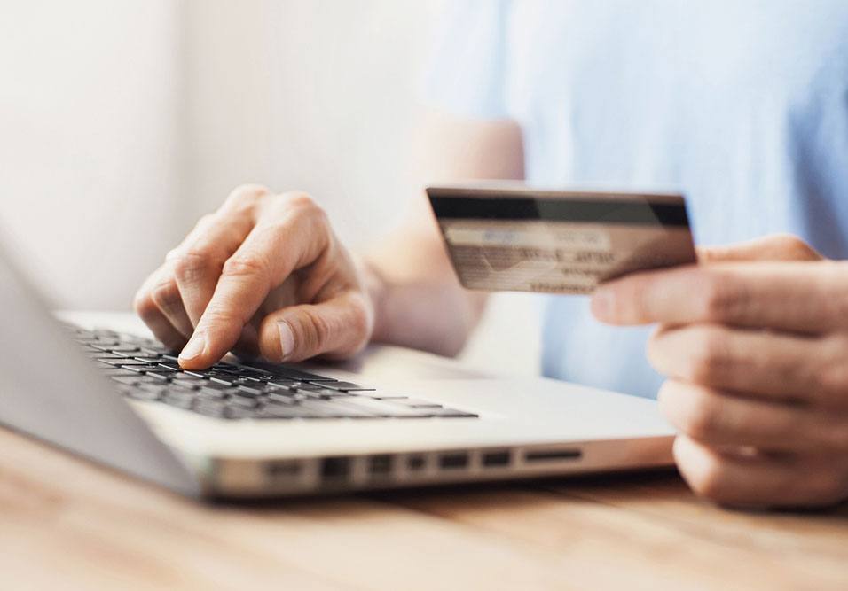Pessoa utilizando um laptop e cartão de crédito, realizando uma compra online ou pagamento digital com foco em segurança na internet. Pessoa utilizando um laptop e cartão de crédito, realizando uma compra online ou pagamento digital com foco em segurança na internet.