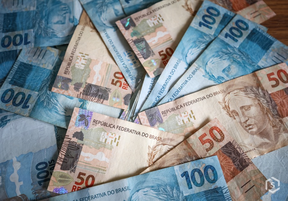 Notas de dinheiro em reais da moeda brasileira, de diferentes valores espalhadas sobre uma superfície de madeira, destacando a economia nacional Notas de dinheiro em reais da moeda brasileira, de diferentes valores espalhadas sobre uma superfície de madeira, destacando a economia nacional