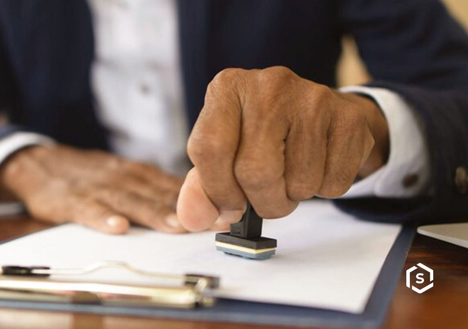 Imagem de uma pessoa carimbando uma ata notarial sobre prancheta, transmitindo profissionalismo e formalidade.