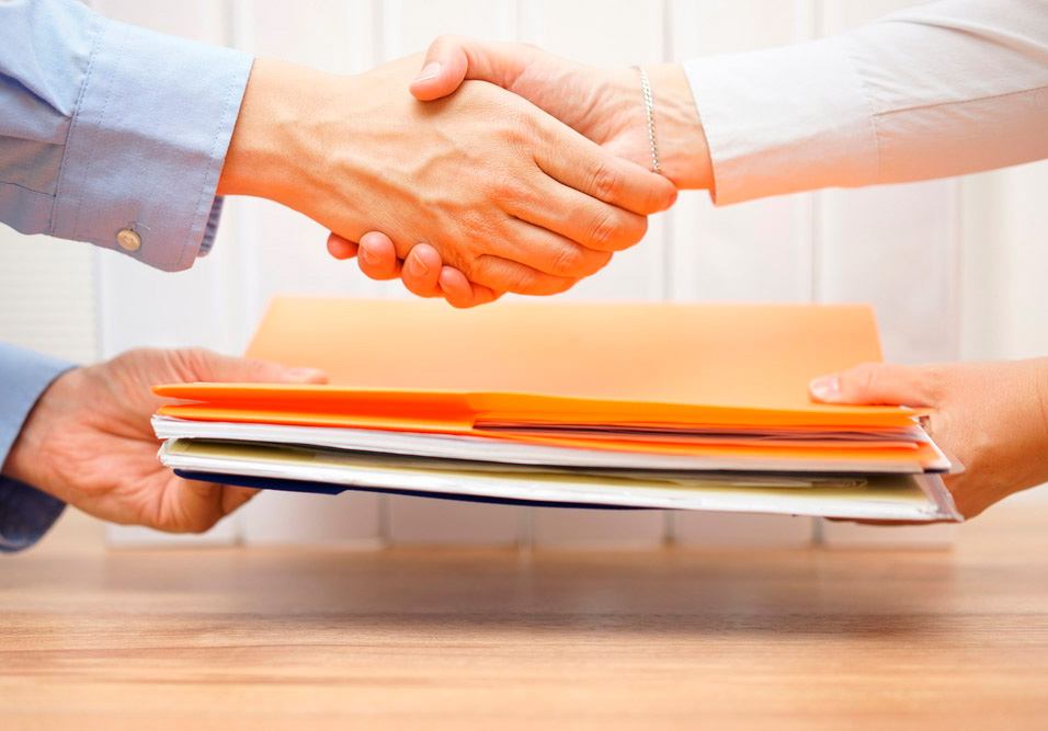 Duas pessoas trocando aperto de mão durante uma assinatura de documento, simbolizando um acordo ou parceria de negócios. Duas pessoas trocando aperto de mão durante uma assinatura de documento, simbolizando um acordo ou parceria de negócios.