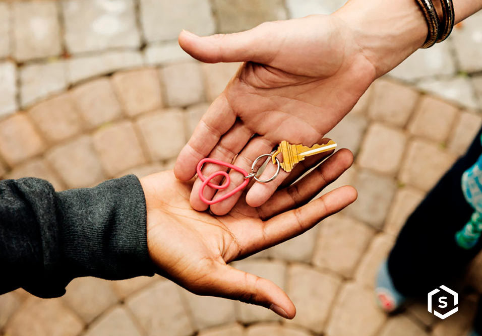 Mão segurando chave com logo do Airbnb 