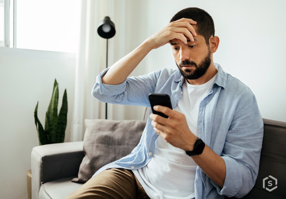 Homem com celular na mão e expressão de preocupação