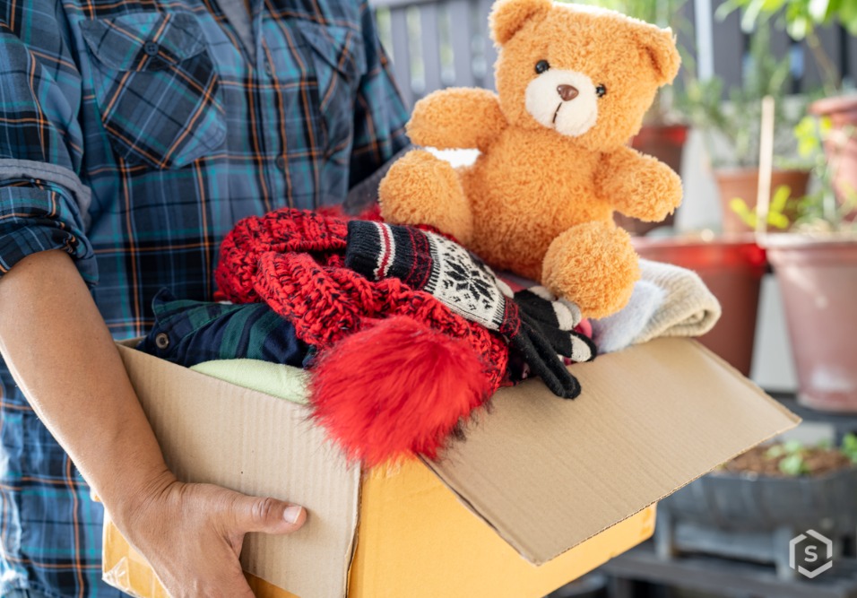 Homem segurando caixa de papelão com urso de pelúcia dentro