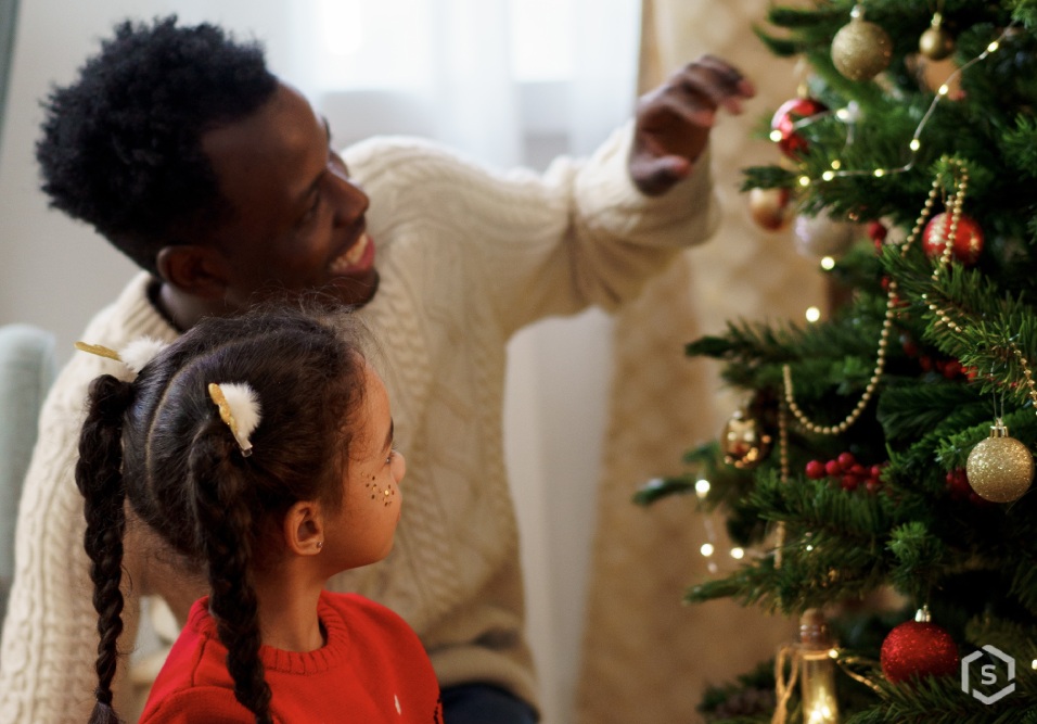 Família celebrando o Natal decorando a árvore de Natal com enfeites e luzes, criando memórias especiais na época natalina.
