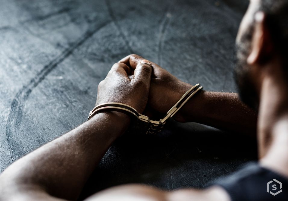 Mãos algemadas em fundo escuro 