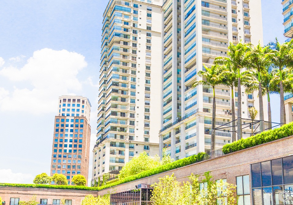 Imagem de arranha-céus modernos em uma área urbana com árvores e céu claro ao fundo, destacando a arquitetura de alto padrão em uma cidade.