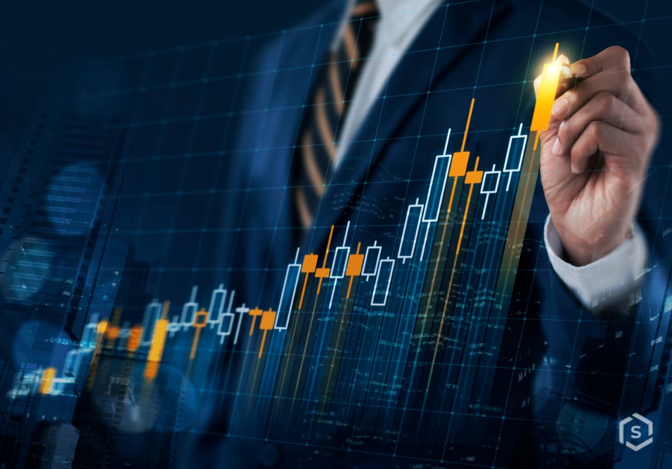 Pessoa de terno e gravata analisa gráficos financeiros com indicadores de alta no mercado de ações, representando investimentos e análise de risco.