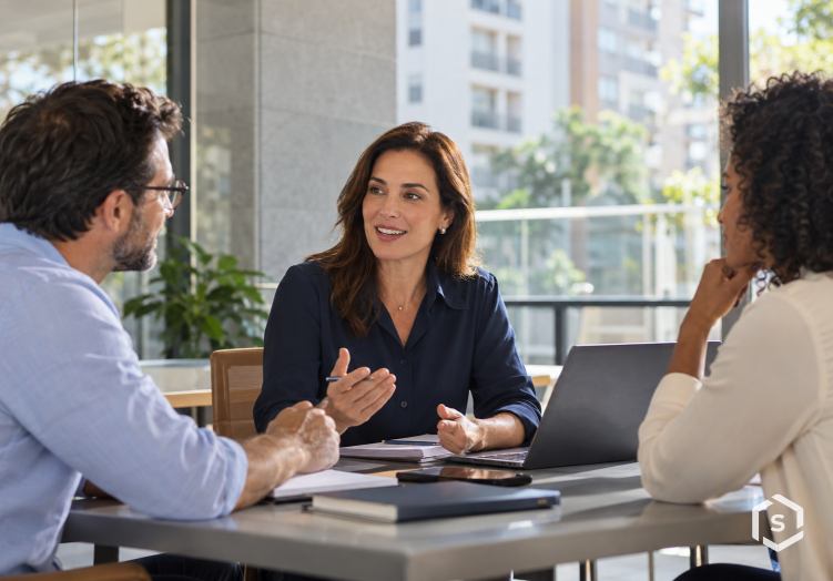 Profissionais conversando em reunião de trabalho em ambiente condominial corporativo.
